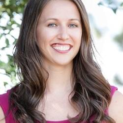 Megan Smith has long, dark hair and is wearing a bright pink shirt.